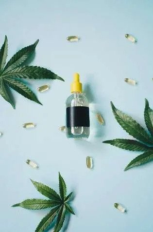 A bottle of cbd oil surrounded by cannabis leaves.