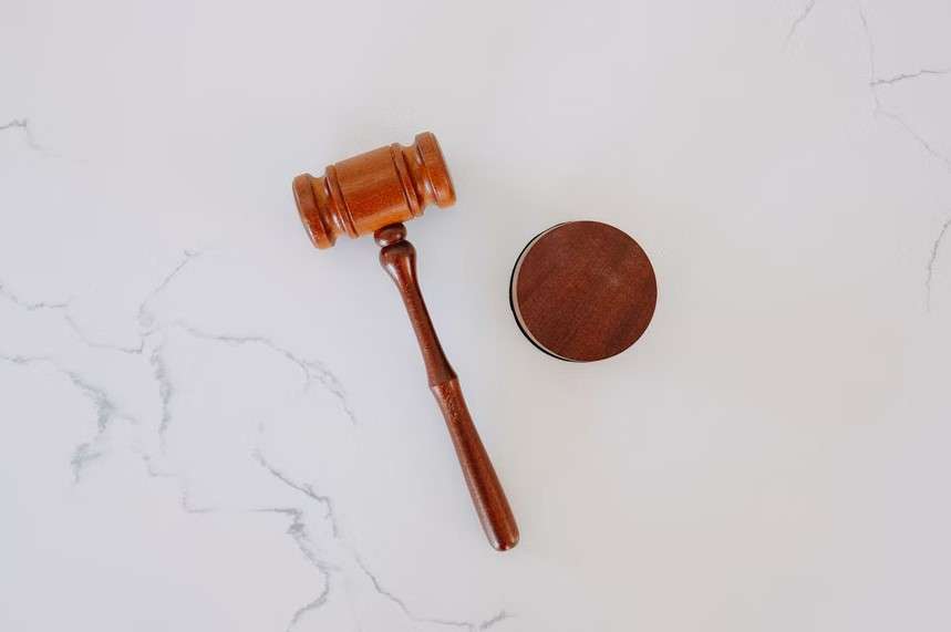 A wooden gavel and a wooden disc on a marble surface.